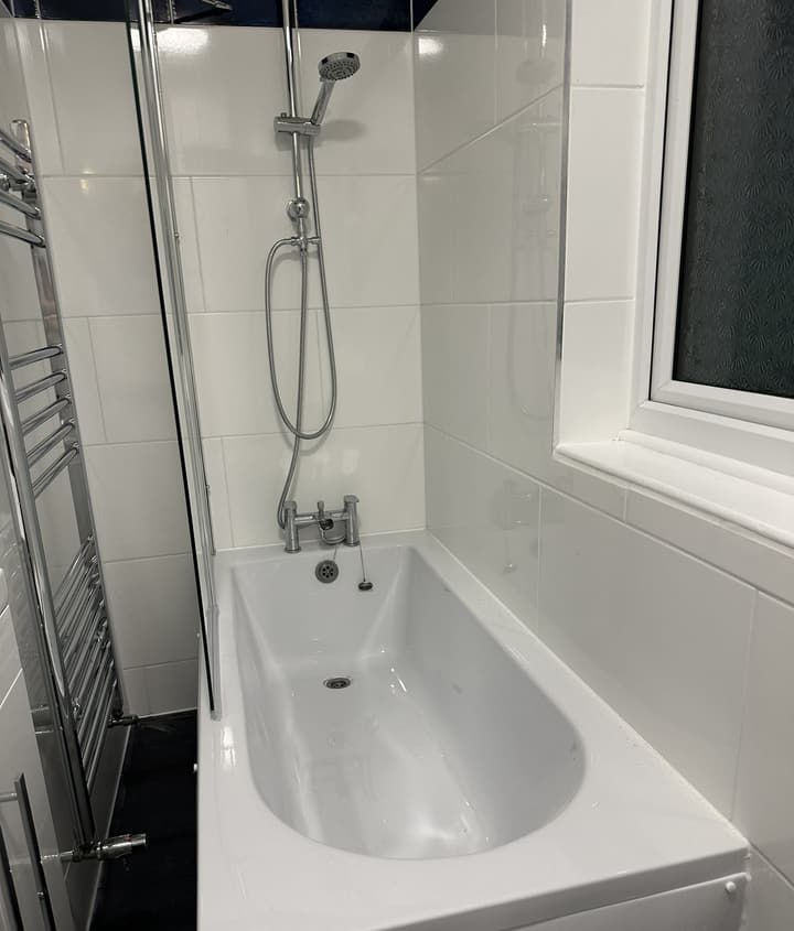 New bath with chrome bath-shower mixer, shower riser and heated towel rail in the renovated Barnet bathroom