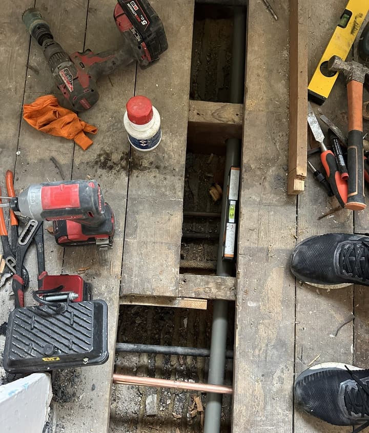 Floorboards lifted in a Barnet bathroom to reroute copper and plastic pipework between the joists