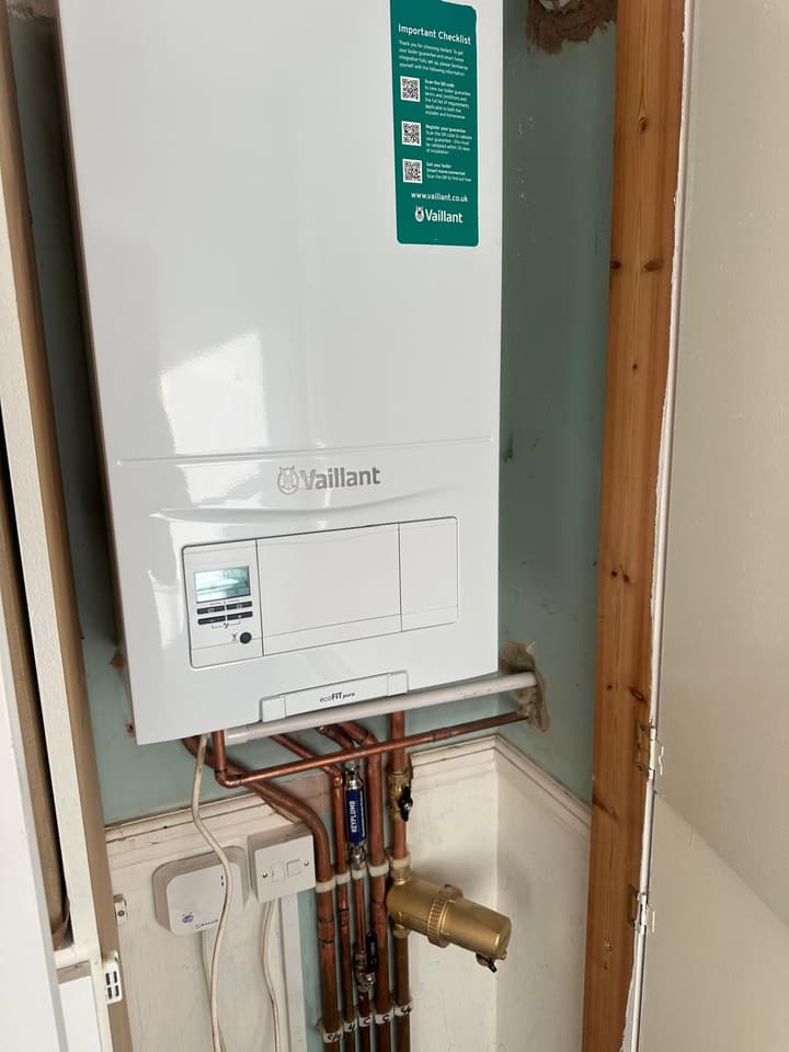 Newly installed Vaillant ecoFIT pure boiler in a cupboard, with neat copper pipework, isolation valves and a system filter below