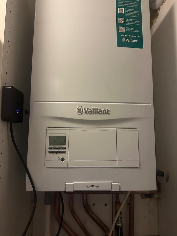 Vaillant ecoFIT pure boiler running after installation, display showing 66 degrees, with a smart thermostat receiver mounted beside it